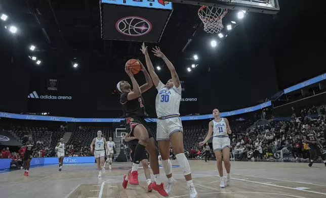 Louisville forward Nyla Harris, left, drives UCLA's forward Timea Gardiner (30) defends during an NCAA college basketball game Monday, Nov. 4, 2024, in Paris, France. (AP Photo/Aurelien Morissard)