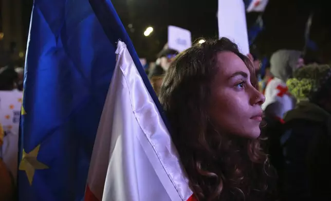 A woman holds EU and Georgian flags during a rally to protest against alleged violations in a recent parliamentary election in Tbilisi, Georgia, Monday, Nov. 11, 2024. (AP Photo/Zurab Tsertsvadze)