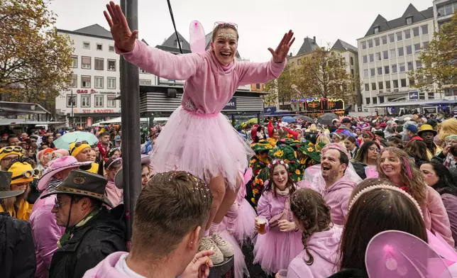 Costumed revelers celebrate at the central Heumarkt while tens of thousands of carnival fools take to the streets of Cologne, Germany, on Monday, November 11, 2024, heralding the official start of the carnival season. (AP Photo/Martin Meissner)