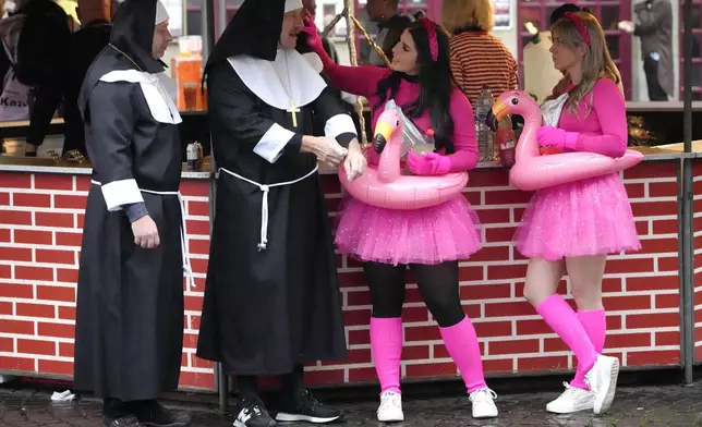 Revelers costumed as nuns and flamingos meet at the central Heumarkt while tens of thousands of carnival fools take to the streets of Cologne, Germany, on Monday, November 11, 2024, heralding the official start of the carnival season. (AP Photo/Martin Meissner)