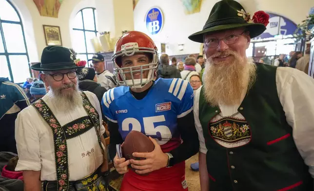 People in Bavarian clothes pose with a NFL supporter inside the traditional 'Hofbraeuhaus' in Munich, Germany, Saturday, Nov. 9, 2024 ahead of the NFL match between the Carolina Panthers and the New York Giants in Munich on Sunday. (AP Photo/Matthias Schrader)