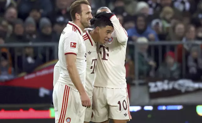 Munich's scorer Jamal Musiala, center, and his teammate Harry Kane, left, celebrate the opening goal during the German Bundesliga soccer match between FC St. Pauli and FC Bayern Munich in Hamburg, Germany, Saturday, Nov. 9, 2024. (Christian Charisius/dpa via AP)