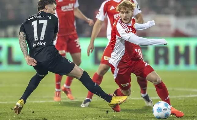 Berlin's Yorbe Vertessen, right, is challenged by Freiburg's Lukas Kübler during the German Bundesliga soccer match between FC Union Berlin and SC Freiburg in Berlin, Friday, Nov. 8, 2024. (Andreas Gora/dpa via AP)