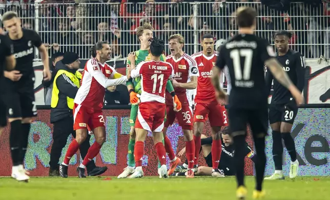 Berlin's players celebrate after goalkeeper Frederik Rönnow, centre, saves a penalty during the German Bundesliga soccer match between FC Union Berlin and SC Freiburg in Berlin, Friday, Nov. 8, 2024. (Andreas Gora/dpa via AP)