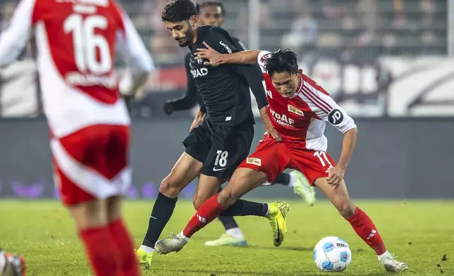 Freiburg's Eren Dinkci, centre, and Berlin's Woo-yeong Jeong, right, fight for the ball during the German Bundesliga soccer match between FC Union Berlin and SC Freiburg in Berlin, Friday, Nov. 8, 2024. (Andreas Gora/dpa via AP)