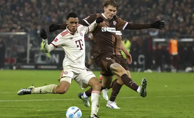 Munich's Jamal Musiala, left, and St. Pauli's Eric Smith, right, challenge for the ball during the German Bundesliga soccer match between FC St. Pauli and FC Bayern Munich in Hamburg, Germany, Saturday, Nov. 9, 2024. (Christian Charisius/dpa via AP)