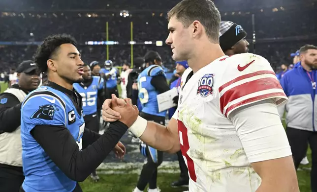 Carolina Panthers quarterback Bryce Young greets New York Giants quarterback Daniel Jones after their overtime win in an NFL football game, Sunday, Nov. 10, 2024, in Munich, Germany. (AP Photo/Lennart Preiss)