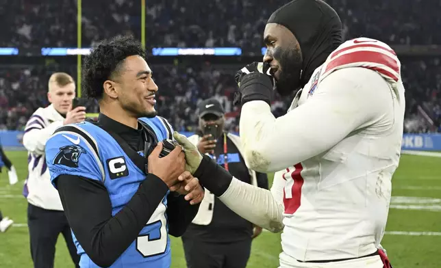 Carolina Panthers quarterback Bryce Young greets New York Giants linebacker Brian Burns after their overtime win in an NFL football game, Sunday, Nov. 10, 2024, in Munich, Germany. (AP Photo/Lennart Preiss)