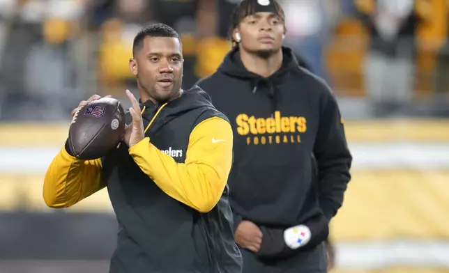 Pittsburgh Steelers quarterback Russell Wilson, left, throws while quarterback Justin Fields watches before an NFL football game against the New York Giants, Monday, Oct. 28, 2024, in Pittsburgh. (AP Photo/Gene J. Puskar)