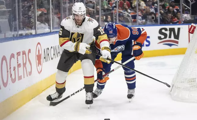 Vegas Golden Knights' Noah Hanifin (15) and Edmonton Oilers' Corey Perry (90) battle for the puck during second period NHL action in Edmonton on Wednesday, November 6, 2024. (Jason Franson/The Canadian Press via AP)