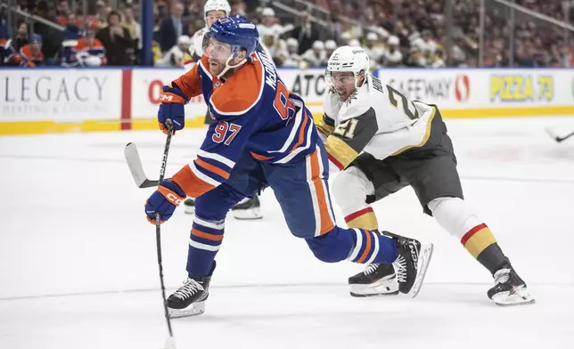 Vegas Golden Knights' Brett Howden (21) tries to defend against Edmonton Oilers' Connor McDavid (97) as he gets the shot off during second period NHL action in Edmonton on Wednesday, November 6, 2024. (Jason Franson/The Canadian Press via AP)