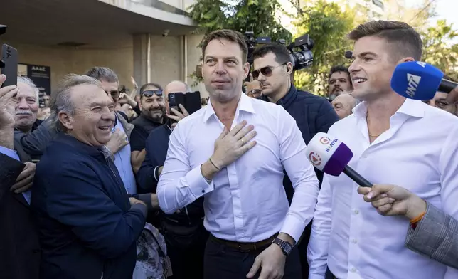 Stefanos Kasselakis, center, a political neophyte who led main opposition SYRIZA party for a year following a stinging election defeat in 2023, is cheered by supporters ahead of an announcement for a new political formation, next to his husband Tyler Mcbeth, right, in Athens, Greece, Saturday, Nov. 9, 2024. (AP Photo/Yorgos Karahalis)