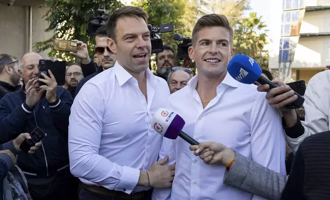 Stefanos Kasselakis, front left, a political neophyte who led main opposition SYRIZA party for a year following a stinging election defeat in 2023, is cheered by supporters ahead of an announcement for a new political formation, next to his husband Tyler Mcbeth, in Athens, Greece, Saturday, Nov. 9, 2024. (AP Photo/Yorgos Karahalis)