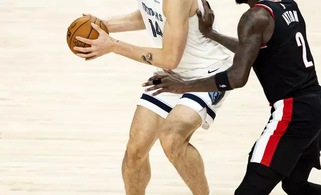 Memphis Grizzlies center Zach Edey, left, dribbles the ball against Portland Trail Blazers center Deandre Ayton during the first half of an NBA basketball game, Sunday, Nov. 10, 2024, in Portland, Ore. (AP Photo/Howard Lao)