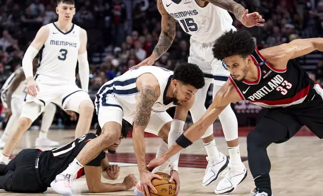 Memphis Grizzlies guard Scotty Pippen Jr., middle, grabs a loose ball against Portland Trail Blazers forward Toumani Camara, right, during the second half of an NBA basketball game Sunday, Nov. 10, 2024, in Portland, Ore. (AP Photo/Howard Lao)