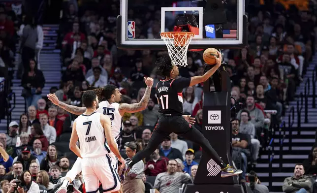 Portland Trail Blazers guard Shaedon Sharpe, center, drives to the hoop against Memphis Grizzlies forward Brandon Clarke, left, during the second half of an NBA basketball game Sunday, Nov. 10, 2024, in Portland, Ore. (AP Photo/Howard Lao)