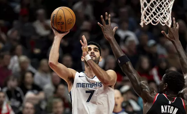 Memphis Grizzlies forward Santi Aldama, left, shoots the ball against Portland Trail Blazers center Deandre Ayton during the first half of an NBA basketball game, Sunday, Nov. 10, 2024, in Portland, Ore. (AP Photo/Howard Lao)