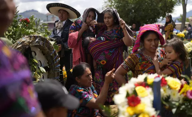 Family members visit the grave of a relative during All Saints Day celebrations at the cemetery of Sumpango, Guatemala, Friday, Nov. 1, 2024, as part of Day of the Dead celebrations. (AP Photo/Matias Delacroix)