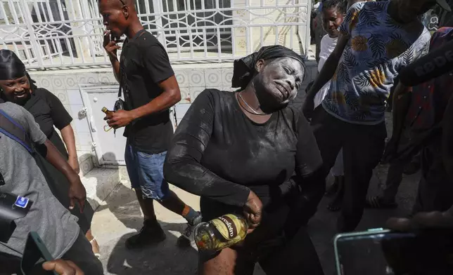 A Vodou believer pours homemade alcohol spiced with hot pepper on herself during the annual Fete Gede festival that celebrates Day of the Dead, honoring the Haitian spirits Baron Samedi and Gede, at the National Cemetery, in Port-au-Prince, Haiti, Friday, Nov. 1, 2024. (AP Photo/Odelyn Joseph)