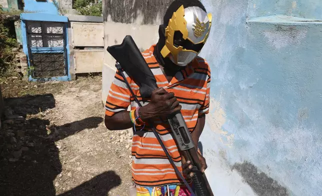 A masked gang member poses for a picture among graves during the annual Fete Gede festival that celebrates Day of the Dead, honoring the Haitian Vodou spirits Baron Samedi and Gede, at the National Cemetery, in Port-au-Prince, Haiti, Friday, Nov. 1, 2024. (AP Photo/Odelyn Joseph)