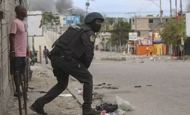 A police officer looks on during an exchange of gunfire between gangs and police in Port-au-Prince, Haiti, Monday, Nov. 11, 2024. (AP Photo/Odelyn Joseph)