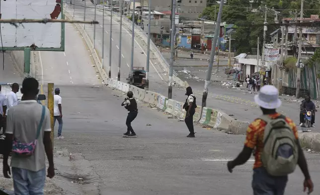 People watch as police officers exchange gunfire with gangs in Port-au-Prince, Haiti, Monday, Nov. 11, 2024. (AP Photo/Odelyn Joseph)