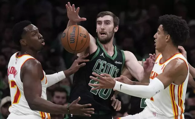 Boston Celtics center Luke Kornet battles for the ball against Atlanta Hawks' Onyeka Okongwu, left, and Jalen Johnson during the first half of an Emirates NBA Cup basketball game, Tuesday, Nov. 12, 2024, in Boston. (AP Photo/Charles Krupa)