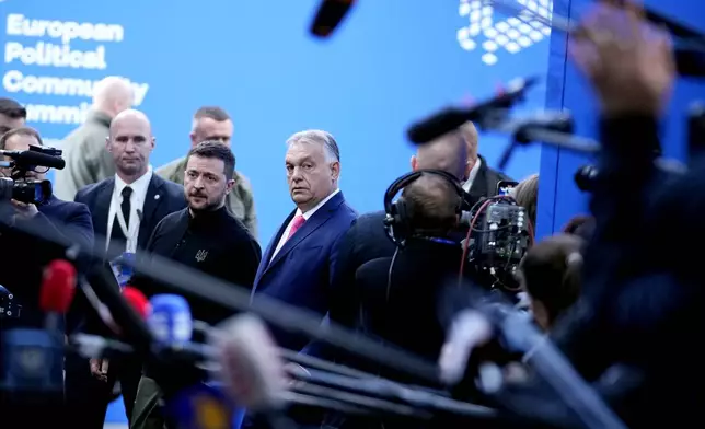 Ukraine's President Volodymyr Zelenskyy, center left, speaks with Hungary's Prime Minister Viktor Orban, center right, as he arrives for the European Political Community (EPC) Summit at the Puskas Arena in Budapest, Hungary, Thursday, Nov. 7, 2024. (AP Photo/Petr Josek)