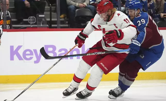 Carolina Hurricanes center Jordan Staal, left, drives past Colorado Avalanche center Nathan MacKinnon to put a shot on goal in the second period of an NHL hockey game Saturday, Nov. 9, 2024, in Denver. (AP Photo/David Zalubowski)