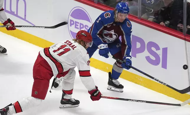 Carolina Hurricanes center Jordan Staal, front, pursues the puck with Colorado Avalanche defenseman John Ludvig in the first period of an NHL hockey game Saturday, Nov. 9, 2024, in Denver. (AP Photo/David Zalubowski)