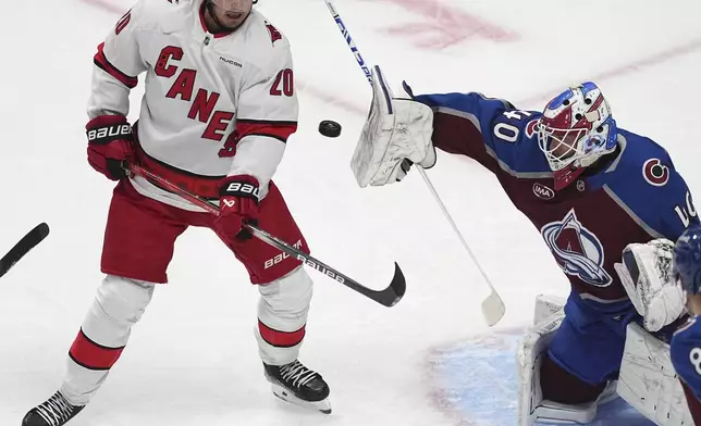 Carolina Hurricanes center Sebastian Aho, left, redirects the puck at Colorado Avalanche goaltender Alexandar Georgiev in the first period of an NHL hockey game Saturday, Nov. 9, 2024, in Denver. (AP Photo/David Zalubowski)