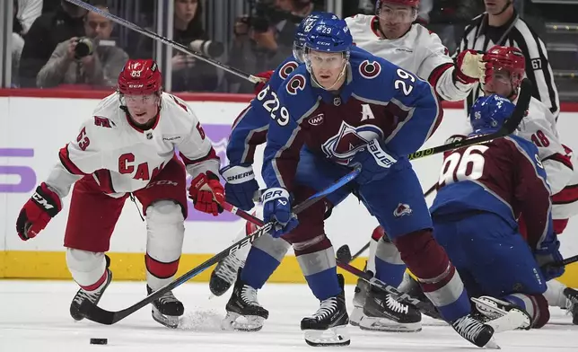 Colorado Avalanche center Nathan MacKinnon, right, collects the puck as Carolina Hurricanes right wing Jackson Blake defends in the second period of an NHL hockey game Saturday, Nov. 9, 2024, in Denver. (AP Photo/David Zalubowski)