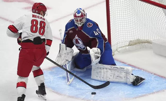 Colorado Avalanche goaltender Alexandar Georgiev, right, stops a shot of the sdtick of Carolina Hurricanes center Martin Necas in the first period of an NHL hockey game Saturday, Nov. 9, 2024, in Denver. (AP Photo/David Zalubowski)