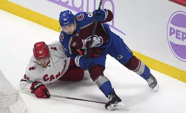 Carolina Hurricanes center Jack Roslovic, left, gets tangled up with Colorado Avalanche left wing Joel Kiviranta as they pursue the puck in the first period of an NHL hockey game Saturday, Nov. 9, 2024, in Denver. (AP Photo/David Zalubowski)