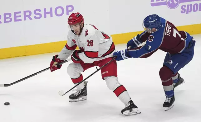 Carolina Hurricanes defenseman Sean Walker, left, passes the puck as Colorado Avalanche defenseman Devon Toews pursues in the first period of an NHL hockey game Saturday, Nov. 9, 2024, in Denver. (AP Photo/David Zalubowski)