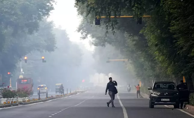 A man crosses a road in the early morning smog the day after the Hindu festival Diwali, in New Delhi, India, Friday, Nov. 1, 2024. (AP Photo/Manish Swarup)