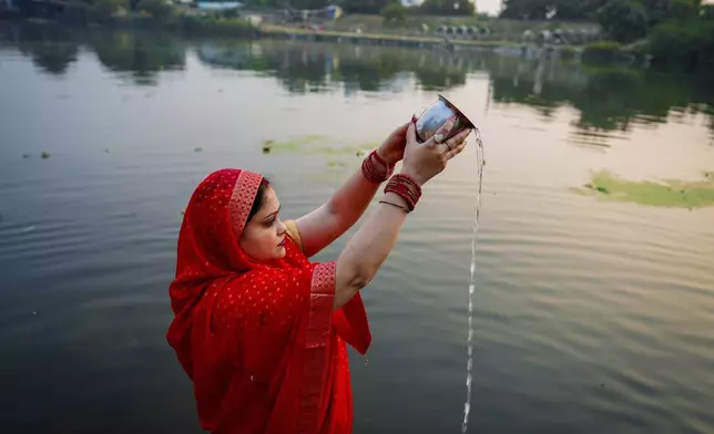 A Hindu woman prays to the sun god as she stands in knee deep waters during Chhath festival performed to thank the Sun god for sustaining life on earth and seeking the divine blessings on the Gomti River in Lucknow, India, Thursday, Nov. 7, 2024. (AP Photo/Rajesh Kumar Singh)