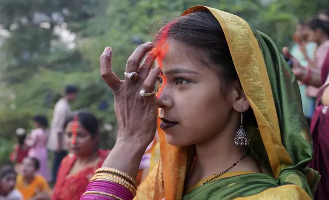 A Hindu woman puts vermilion powder on the forehead of another during Chhath festival performed to thank the Sun god for sustaining life on earth and seeking the divine blessings on the Gomti River in Lucknow, Thursday, Nov. 7, 2024. (AP Photo/Rajesh Kumar Singh)