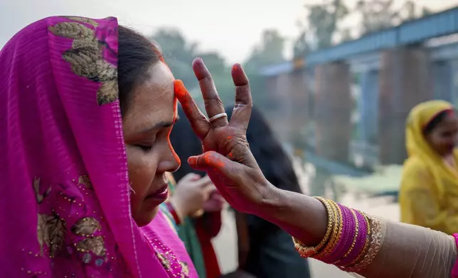 A Hindu woman puts vermilion powder on the forehead of another during Chhath festival performed to thank the Sun god for sustaining life on earth and seeking the divine blessings on the Gomti River in Lucknow, India, Thursday, Nov. 7, 2024. (AP Photo/Rajesh Kumar Singh)