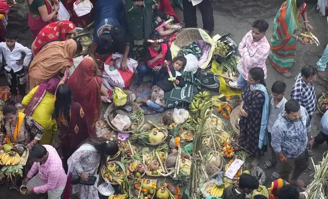 A child lies next to offerings brought by devotees on the banks of the river Yamuna during Chhath festival in Noida, near New Delhi, India, India, Friday, Nov. 8, 2024. (AP Photo/Manish Swarup)