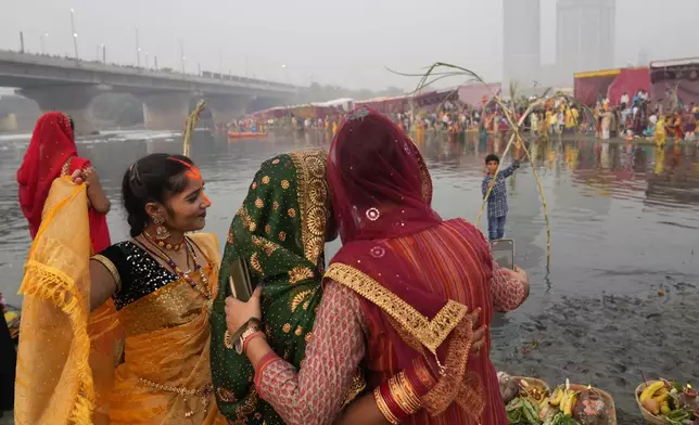 Devotees take selfies on the banks of the river Yamuna before offering prayer to the sun god during Chhath festival in Noida, near New Delhi, India, Thursday, Nov. 7, 2024. (AP Photo/Manish Swarup)