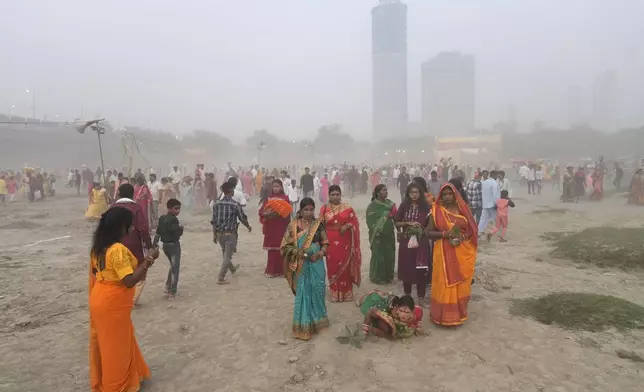 A devotee prostrates on the bank of the river Yamuna to offer prayers as smog envelops the skyline during Chhath festival in Noida, near New Delhi, India, Thursday, Nov. 7, 2024. (AP Photo/Manish Swarup)