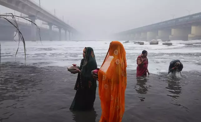 Devotees pray on the banks of the river Yamuna as toxic foam flows during Chhath festival in Noida, near New Delhi, India, Friday, Nov. 8, 2024. (AP Photo/Manish Swarup)