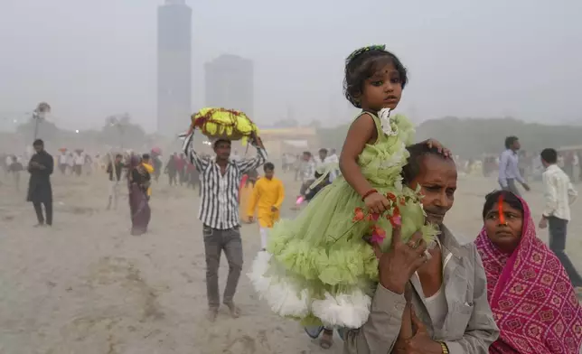 Devotees arrive on the banks of the river Yamuna to offer prayers as smog envelops the skyline during the Chhath festival in Noida, near New Delhi, India, Thursday, Nov. 7, 2024. (AP Photo/Manish Swarup)