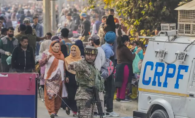 An Indian paramilitary soldiers guards as others inspect the site of a grenade explosion at a marketplace, in Srinagar, Indian controlled Kashmir, Sunday, Nov. 3, 2024. (AP Photo/Mukhtar Khan)