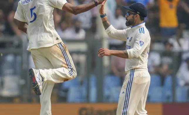 India's Washington Sundar, left, and Virat Kohli celebrates the dismissal of New Zealand's captain Tom Latham during the first day of the third cricket test match between India and New Zealand at Wankhede Stadium, in Mumbai, India, Friday, Nov. 1, 2024.(AP Photo/Rajanish Kakade)