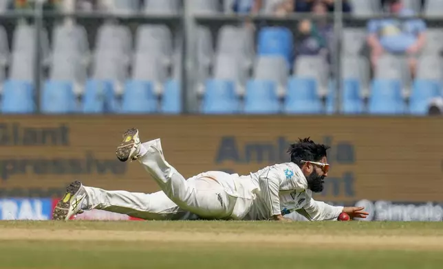 New Zealand's Aijaz Patel dives to field a ball during the third day of the third cricket test match between India and New Zealand at Wankhede Stadium, in Mumbai, India, Sunday, Nov. 3, 2024.(AP Photo/Rajanish Kakade)