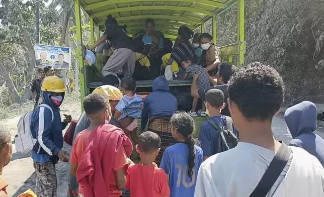 In this image made from AP video, people board a truck as they evacuate their village in an area affected by the eruption of Mount Lewotobi Lake-Laki in East Flores, Indonesia, Tuesday, Nov. 5, 2024. (AP Photo)