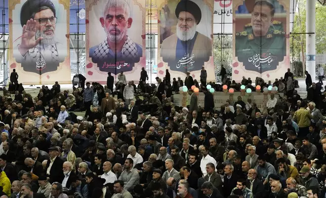 Iranian worshippers sit under portraits of Iranian Revolutionary Guard Gen. Abbas Nilforushan, right, Hezbollah leader Hassan Nasrallah, second right, Hamas leader Yahya Sinwar, second left, and Nasrallah's presumed successor, Hashem Safieddine, all of whom were killed by Israeli strikes, during Friday prayer ceremony at the Tehran University campus, Friday, Nov. 8, 2024, in Tehran, Iran. (AP Photo/Vahid Salemi)