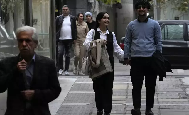 People walk on a sidewalk in northern Tehran, Iran, Thursday, Nov. 7, 2024. (AP Photo/Vahid Salemi)